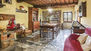 Un comedor rústico con mesa y sillas de madera, chimenea de piedra y estantería.