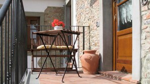 Un balcón con mesa, sillas y una planta en maceta.