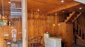 Un intérieur en bois comprenant un comptoir d’accueil, des chaises et un escalier.