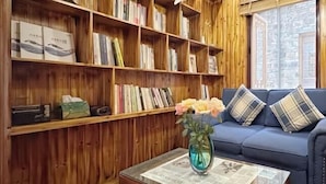 Un salon chaleureux avec une bibliothèque en bois remplie de livres et un vase de fleurs posé sur une table basse.