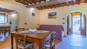 Un comedor acogedor con una mesa y sillas de madera, un banco y vistas al jardín a través de un acceso abierto.