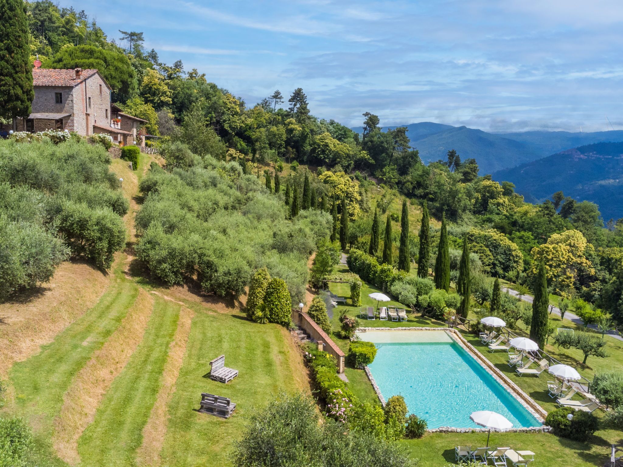 Une villa située sur une colline, dotée d’une piscine, d’un jardin et offrant une vue sur les montagnes.
