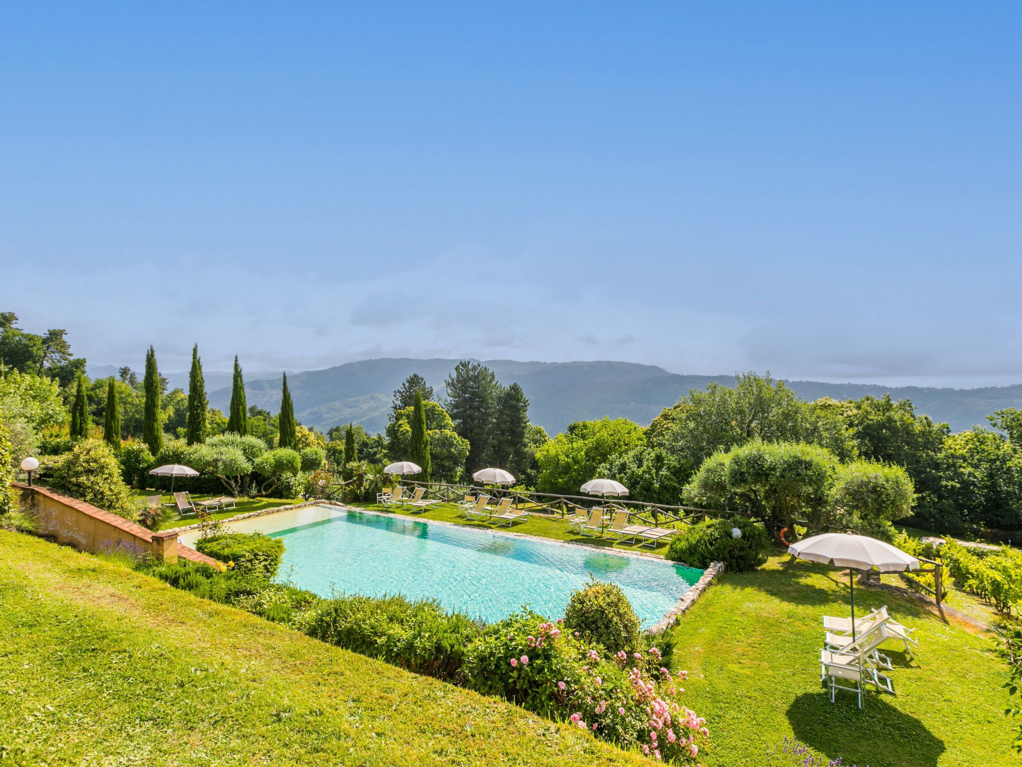 A pool with a clear view of the surrounding landscape, including trees and distant mountains.