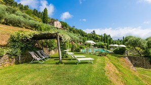 A hillside garden with a pool, lounge chairs, and a pergola. - La Cupola: Lavanda by Interhome (Pescia)