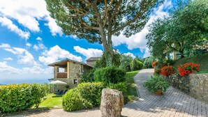 A stone house with a patio, surrounded by lush greenery and a view of the sea. - La Cupola: Lavanda by Interhome (Pescia)