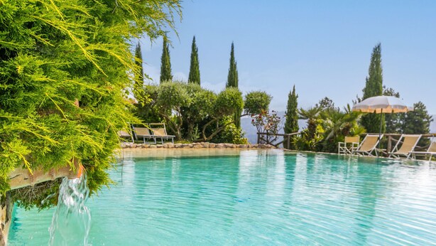 A clear pool with lounge chairs and a waterfall feature. - La Cupola: Lavanda by Interhome (Pescia)