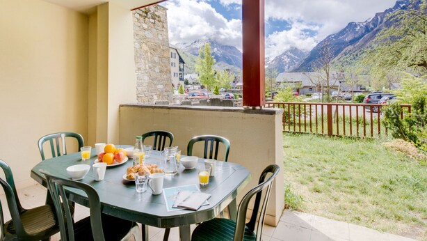 A dining table set with breakfast items, a stone wall, and a mountain view.