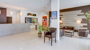 A modern hotel lobby with a reception desk, seating area, and a wall-mounted ski poster.