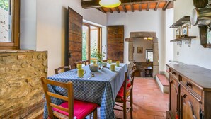 Un comedor rústico con mantel a cuadros, sillas de madera y pared de piedra.