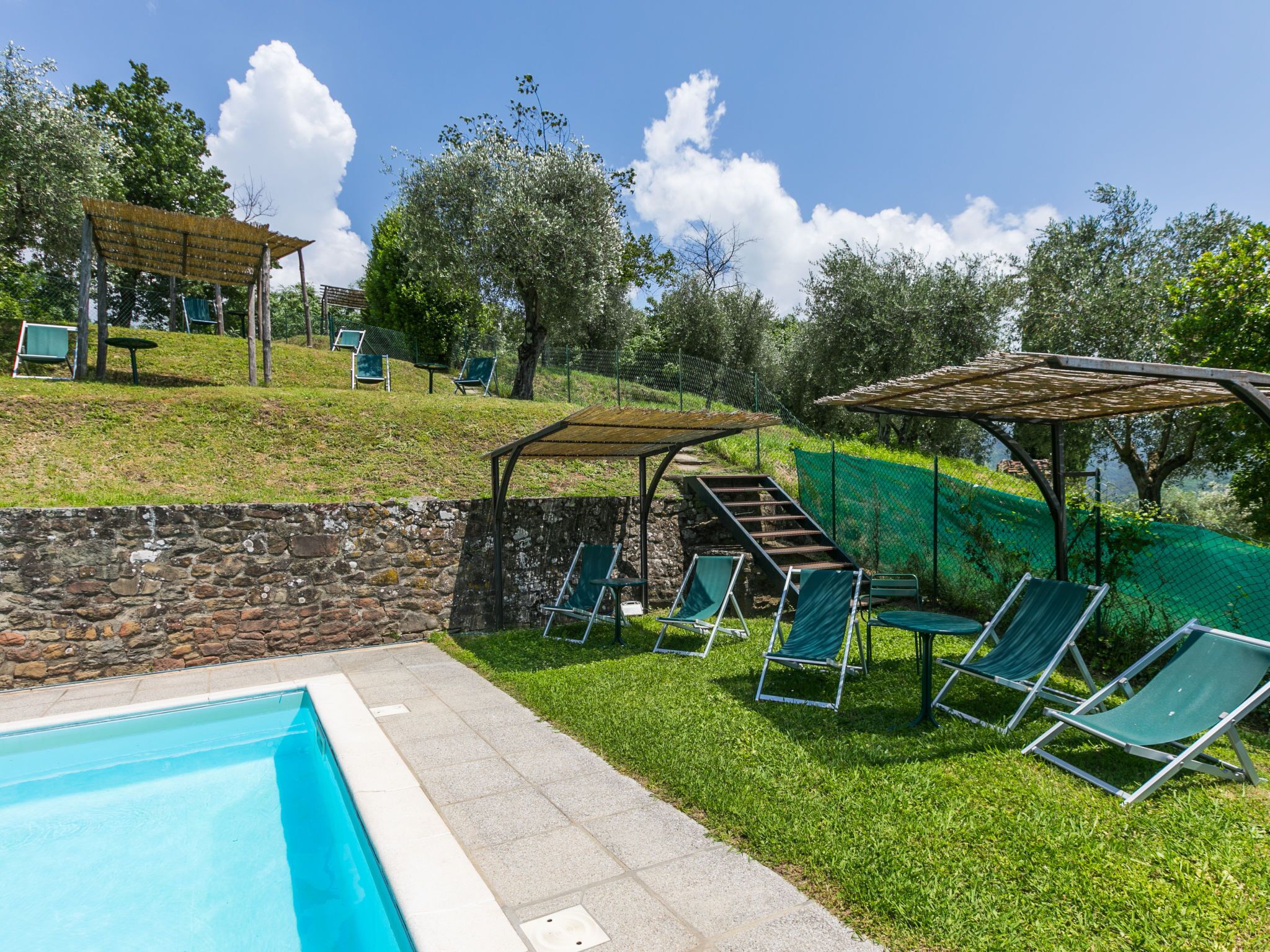 A swimming pool with lounge chairs and a pergola.