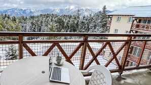 En balkong med ett bord och stolar, med utsikt över ett snötäckt bergskedja.