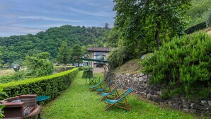 A hillside garden with a stone wall, a small building, and several blue chairs. - Podere Piastriccio / Apt.Piccolo by Interhome (Pescia)