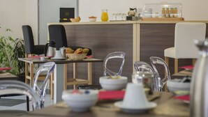 Un caffè moderno con un bancone in legno, sedie trasparenti in vetro e una varietà di prodotti alimentari esposti.