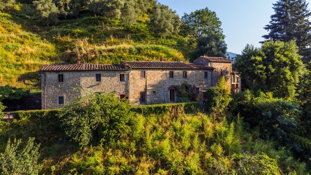 A stone building with multiple windows and a tiled roof, surrounded by lush greenery and trees. - Podere Villa / Apt. Gigi by Interhome (Pescia)