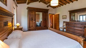 A bedroom with a large bed, wooden wardrobe, and a mirror. - Podere Villa / Apt. Gigi by Interhome (Pescia)