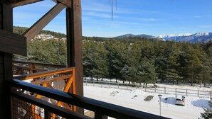 A wooden balcony with a view of a snowy landscape, trees, and mountains in the distance. - Appart Vacances Pyrénées 2000 by Interhome (Bolquere)