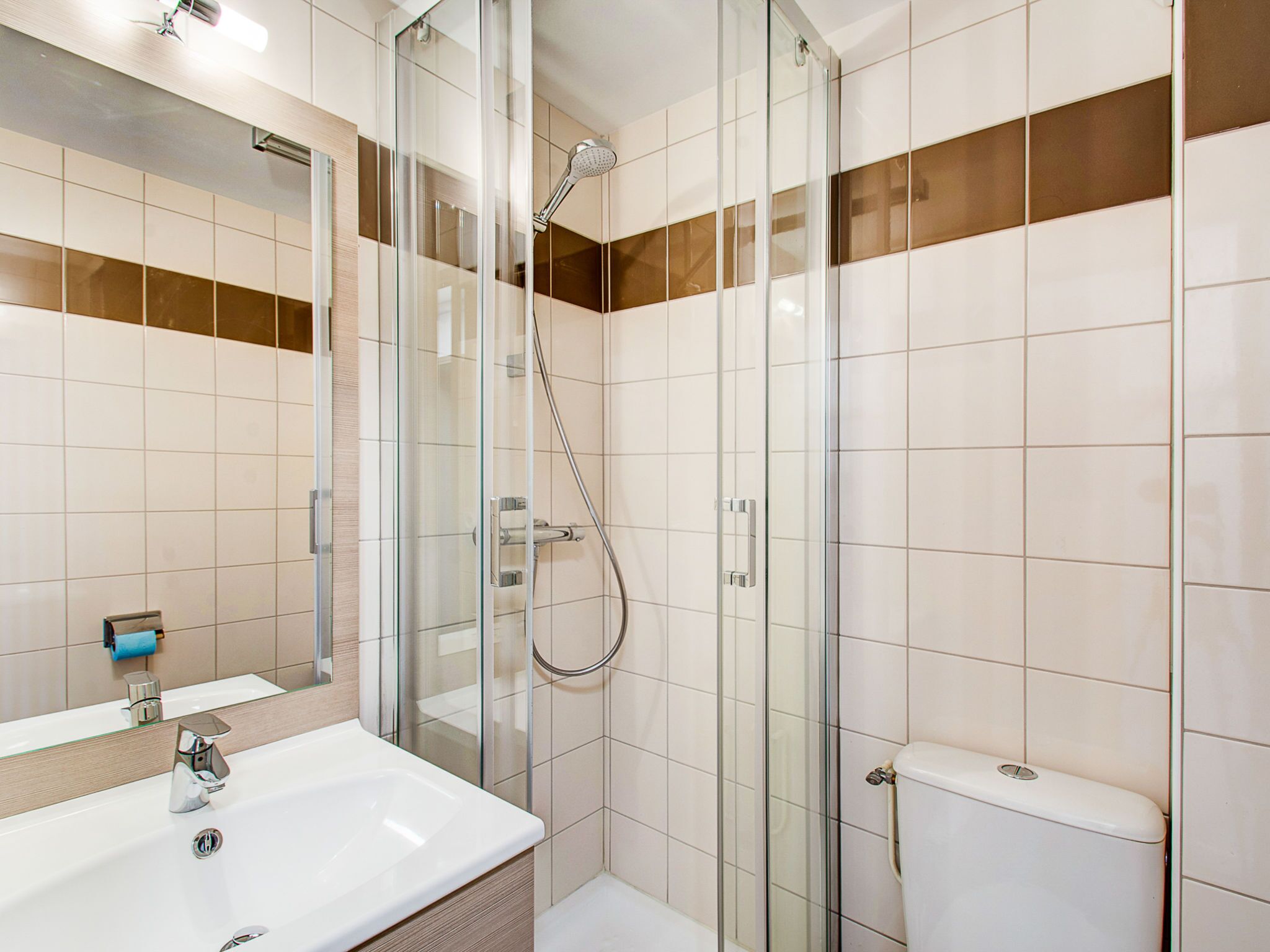 Un baño moderno con ducha de vidrio, lavamanos blanco y retrete.