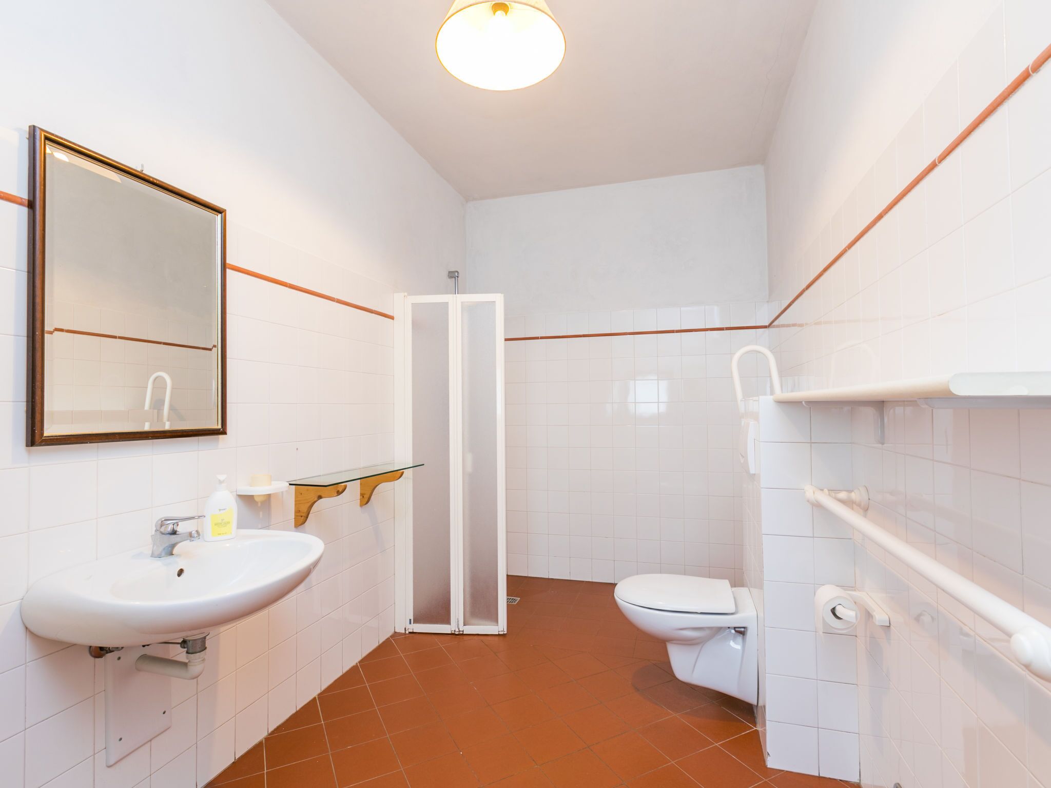 A modern bathroom with a white sink, mirror, and toilet.
