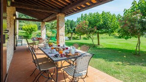 Une terrasse extérieure avec une table dressée pour le petit-déjeuner, entourée de piliers en pierre et d’une pergola en bois.