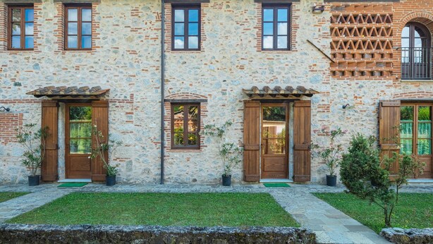 Un bâtiment à deux étages, doté d’une façade en pierre, de portes en bois et d’un toit recouvert de tuiles.