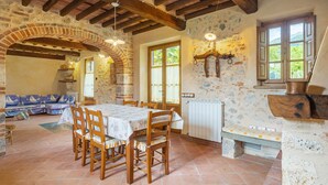 Un coin repas au style rustique, agrémenté d’une arche en briques, de poutres en bois et d’un mur en pierre.