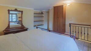 A bedroom with a bed, a wooden wardrobe, a mirror, and a shelf unit. - L'Oliveto by Interhome (Camaiore)