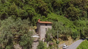 A stone building with a red roof, surrounded by lush greenery and a winding road. - L'Oliveto by Interhome (Camaiore)