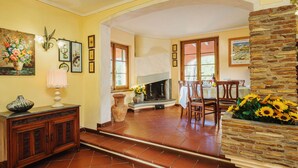 A dining area with a fireplace, wooden chairs, and a table set for dining. - Costacce by Interhome (Camaiore)