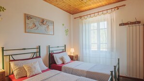 A room with two beds, a wooden ceiling, a painting, a window with curtains, and a radiator. - Paradiso by Interhome (Camaiore)