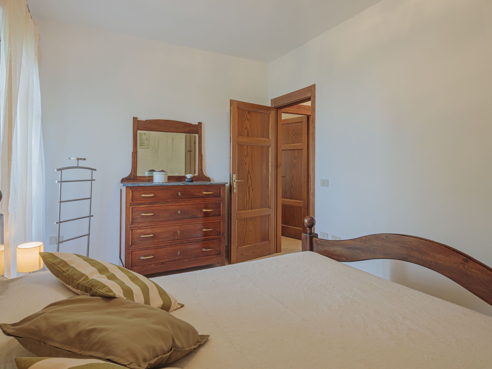A bedroom with a bed, wooden dresser, and a door.