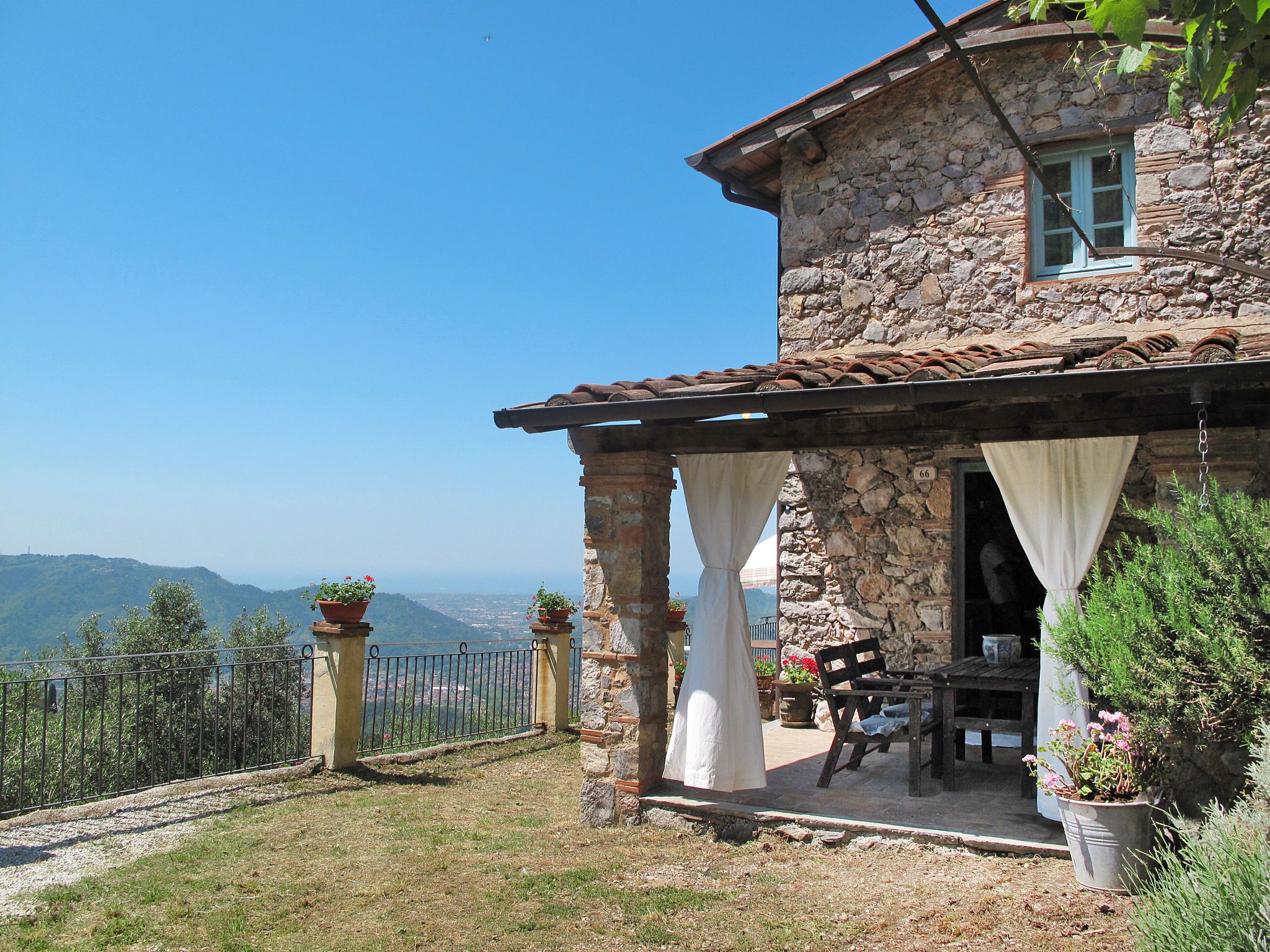 A stone building with a covered patio, a view of the mountains, and a number '66' on the wall.