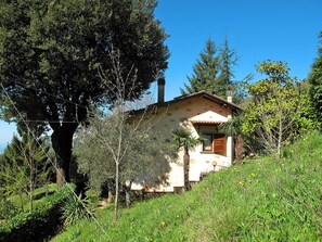 A rustic house with a stone facade, a wooden door, and a small porch.