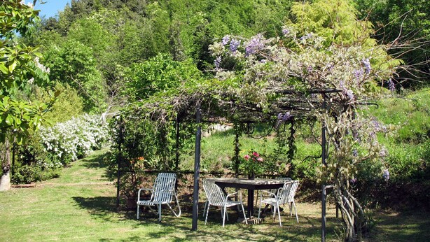 A garden with a pergola, two tables, and four chairs.