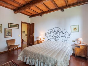 A bedroom with a large bed, wooden headboard, and a rustic ceiling.