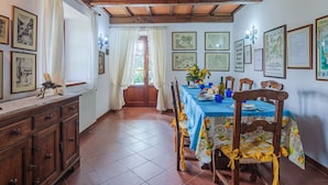 A dining area with a wooden ceiling, tiled floor, and a table set for four.