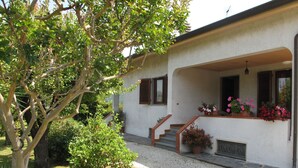 Una casa con un porche cubierto, una escalera que conduce a la entrada y varias macetas con plantas.