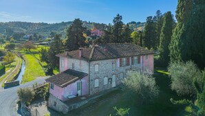 Un edificio de piedra con fachada rosa, rodeado de follaje y un cielo despejado.