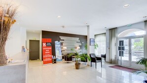 Un moderno vestíbulo de hotel con recepción, zona de estar y un gran ventanal que da al exterior.