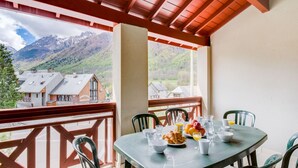 Comedor con una mesa dispuesta para dos personas, con vistas a un paisaje montañoso.