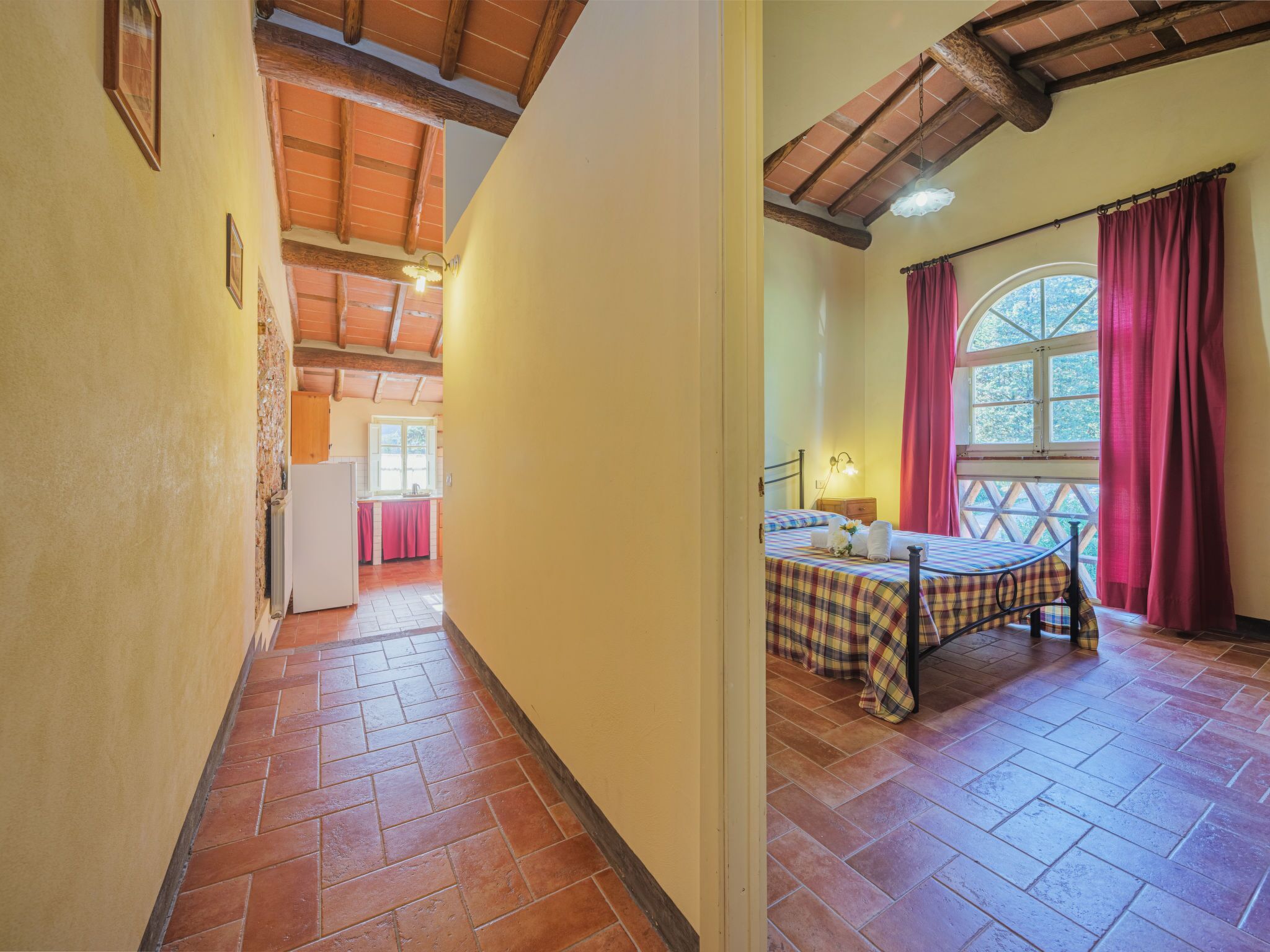 A bedroom with a bed, a window with curtains, and a view of the outside.
