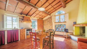 Una cocina amplia con techo de madera, pared de piedra y zona de comedor con mesa y sillas.