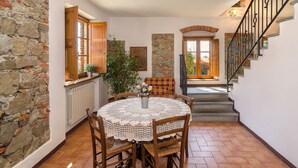 A dining area with a round table, chairs, a potted plant, and a staircase leading to an upper floor. - Giuseppe by Interhome (Lucca)
