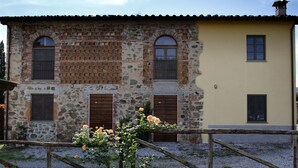 A two-story building with a stone facade and wooden shutters, featuring a garden with roses and a gravel pathway. - Giuseppe by Interhome (Lucca)