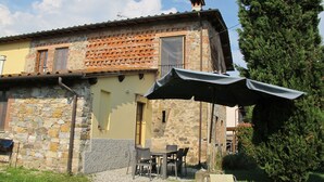 A rustic stone building with a tiled roof, outdoor seating, and a large tree nearby. - Giuseppe by Interhome (Lucca)