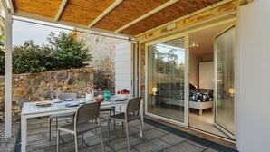 An outdoor patio with a table set for two, surrounded by stone walls and a wooden ceiling. - Rustico dei Canali by Interhome (Lucca)