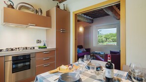 A modern kitchen with stainless steel appliances, a checkered tablecloth, and a dining area with a view of the outdoors. - Rustico dei Canali by Interhome (Lucca)