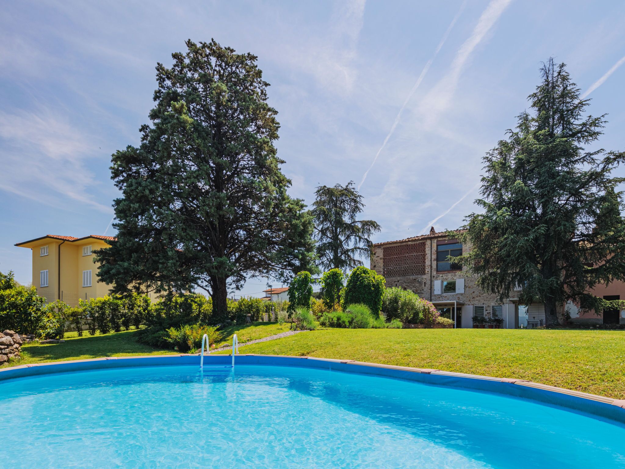 Une piscine entourée d’arbres et de bâtiments.