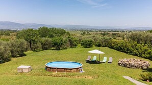 A backyard with a swimming pool, lounge chairs, and a stone wall. - Rustico dei Canali by Interhome (Lucca)
