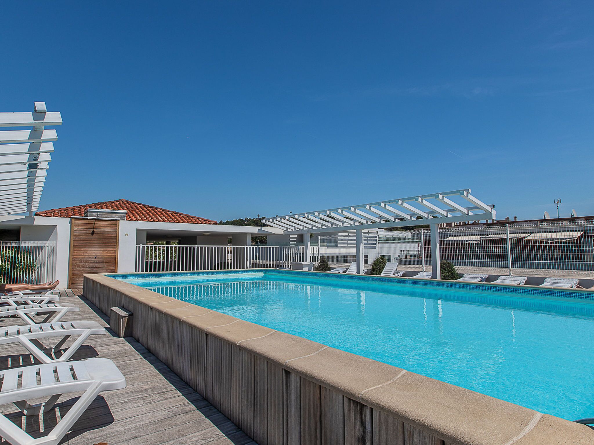 A rooftop pool with lounge chairs and a pergola.