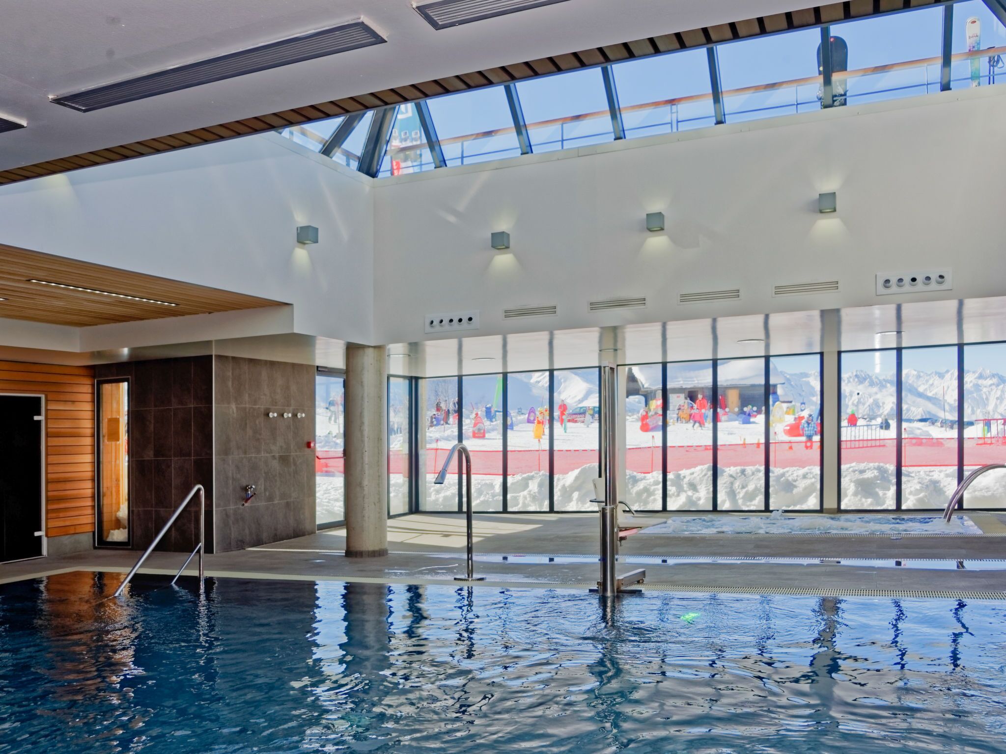 An indoor swimming pool with a view of a snowy outdoor area through large windows.